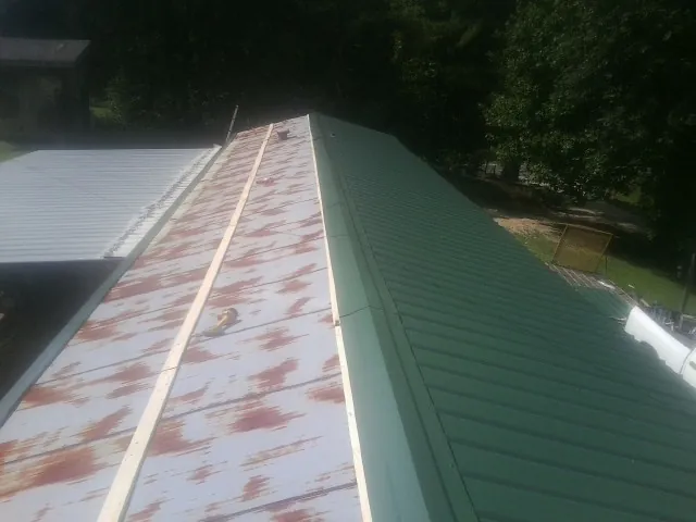 Old rusted panels beside newly installed green metal roofing — Wind Damage Roof Repair by Roofing Brothers in Pleasant Valley