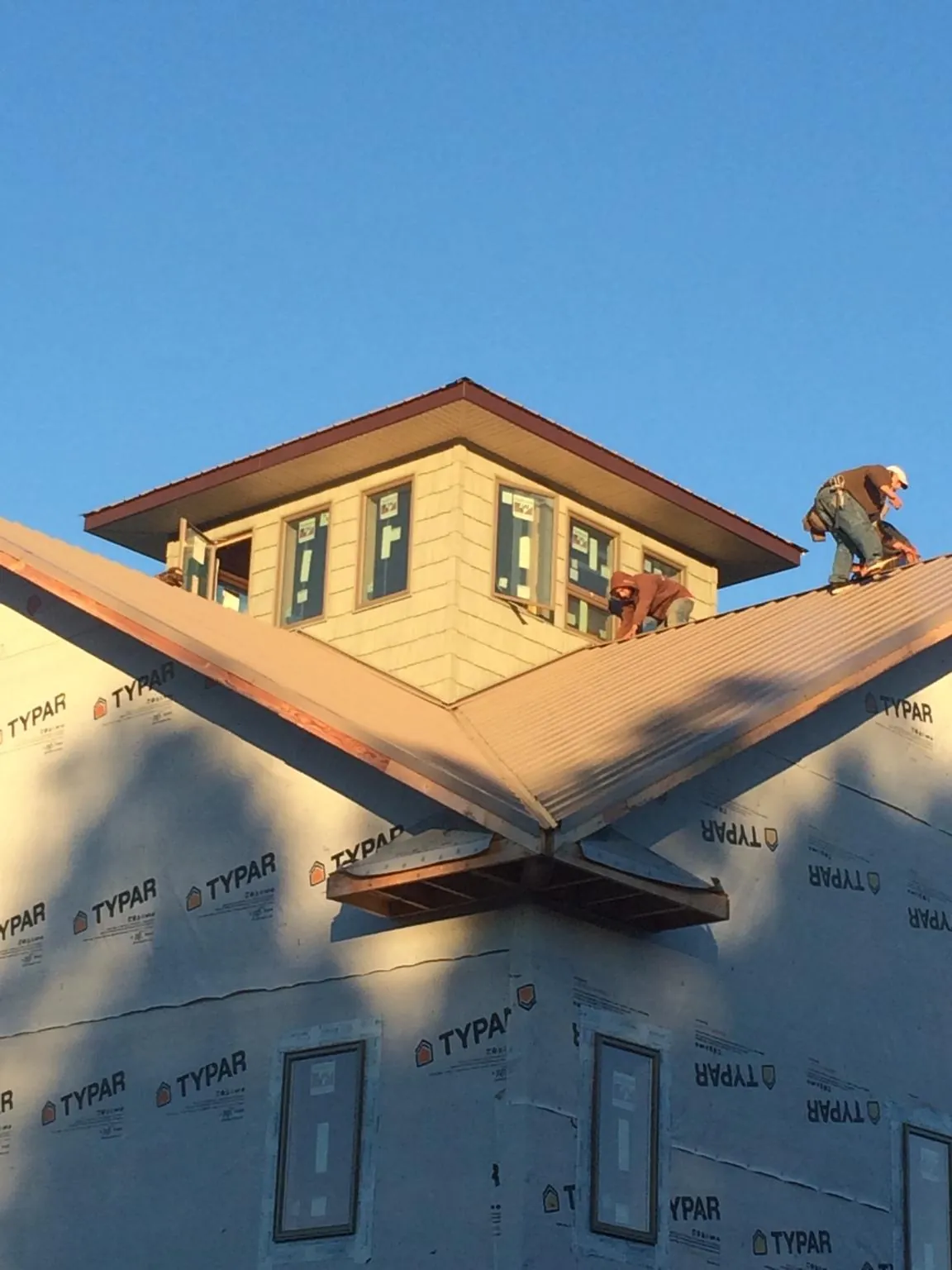 Roofers working around a rooftop cupola on a new metal roof at sunset — Roof Waterproofing in Pleasant Valley by Roofing Brothers